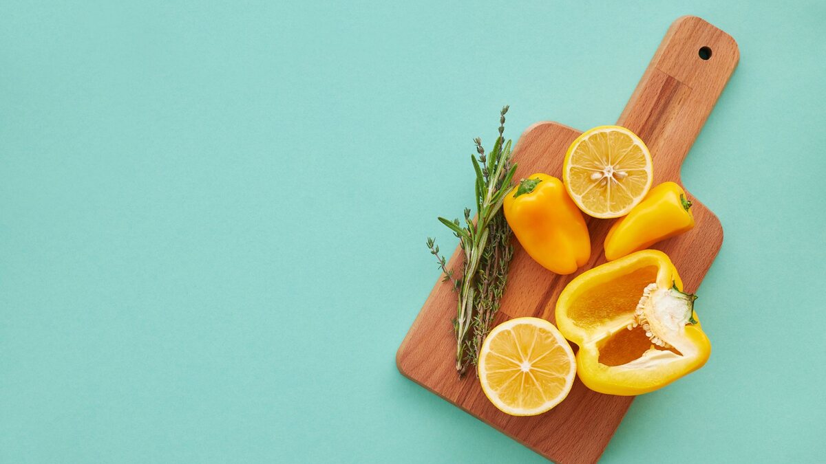 Citrons entiers et coupés posés sur une planche avec des herbes fraîches